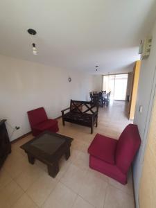 uma sala de estar com cadeiras vermelhas e uma mesa em Alq Toba- Hermoso Duplex en Bajo la Viña em San Salvador de Jujuy