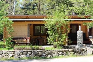 a log cabin with a stone wall in front of it at Wooden lodge with jacuzzi in Rečica ob Savinji