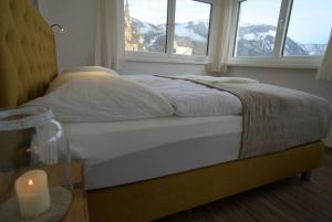 a bed with a candle in a room with windows at Dangos Mountainview Gosau in Gosau