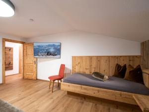 a bedroom with a wooden bed and a red chair at Bauernhof Vordermühltal in Itter