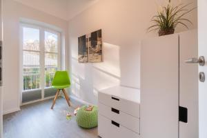 ヴィーク・アウフ・フェールにあるHaus am Leuchtturm Wohnung 3の白い部屋(緑の椅子、ドレッサー付)