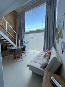 a living room with a couch and a large window at Ybira Loft in Araxá