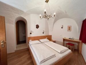 a bedroom with a bed and a chandelier at Roter Adler in Caldaro