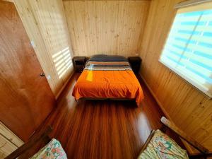 een kleine slaapkamer met een bed in een houten kamer bij Acogedora cabaña en Pelluhue a metros de la playa in Pelluhue