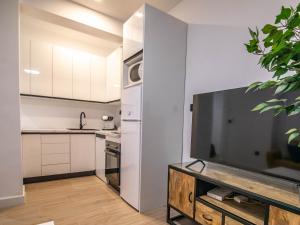 a kitchen with white cabinets and a large screen tv at tuGuest Avenida Madrid in Granada