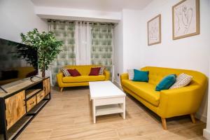 sala de estar con 2 sofás amarillos y TV en tuGuest Avenida Madrid, en Granada
