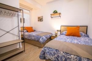 1 dormitorio con 2 camas con almohadas de color naranja en tuGuest Avenida Madrid, en Granada