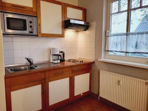 a small kitchen with a sink and a microwave at Appartementhaus Ulmenschloesschen in Kühlungsborn