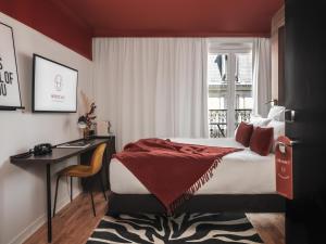 a bedroom with a bed and a desk and a window at Seven Hotel in Paris