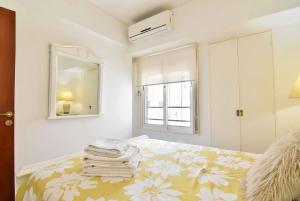 een slaapkamer met een bed, een spiegel en een raam bij Recoleta excelente ubicación in Buenos Aires