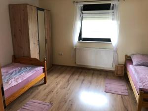 1 Schlafzimmer mit 2 Betten, einem Fenster und Holzböden in der Unterkunft Rupp Ferienwohnung in Wallerfangen