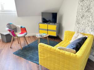 a living room with a yellow couch and a chair at La petite Venise du Loir in Vendôme
