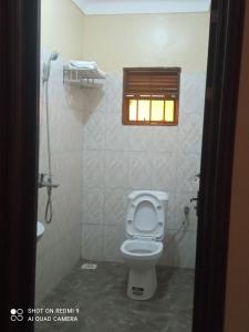 a bathroom with a toilet and a window at Palm Star Motel in Fort Portal
