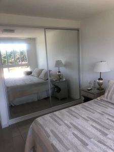 Un dormitorio con una pared de espejo con una cama y una ventana en Inolvidable paz y belleza, en Punta del Este