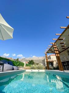 a swimming pool with an umbrella next to a house at VILLAS BALATSOURAS in Paleros