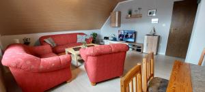 una sala de estar con 2 sillas rojas y una mesa. en Haus im Wiesengrund, en Esens