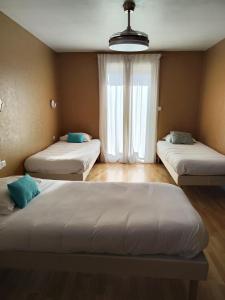 3 camas en una habitación con ventana en LE SPORTING, en Beaumont-sur-Lèze