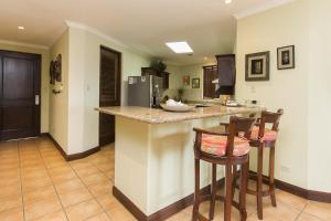 een keuken met een aanrecht en 2 barkrukken bij Bougainvillea 9305 Luxury Apartment - Reserva Conchal in Playa Conchal