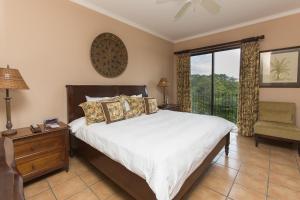 een slaapkamer met een bed, een stoel en een raam bij Bougainvillea 9305 Luxury Apartment - Reserva Conchal in Playa Conchal