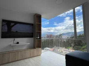 sala de estar con TV grande y ventana grande en Dpo 2 dorm(parqueadero wifi Netflix)vista pan. UIO, en Quito