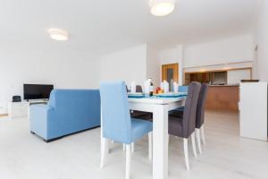 a dining room with a white table and blue chairs at T3 Bliss by Seewest in Albardeira