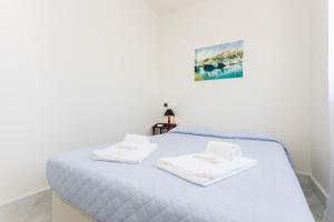 a white bedroom with a bed with towels on it at Fabrica da Ribeira Apartment by Seewest in Lagos