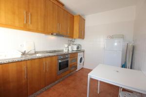 cocina con armarios de madera y nevera blanca en T3 Casa dos Arcos by Seewest, en Salema