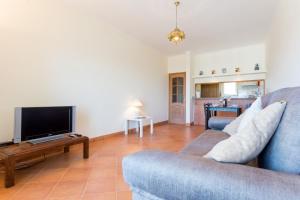 sala de estar con sofá azul y TV en T1 Sol by Seewest, en Albardeira