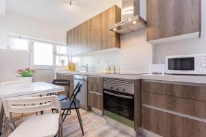 T3 Moinho by Seewest في Santo Amaro: مطبخ مع خزائن خشبية وطاولة وكراسي