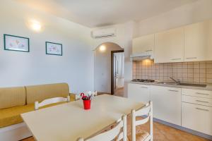 een keuken en eetkamer met een witte tafel en stoelen bij Residenza Le Farfalle in Tergu