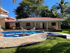 a man sitting in a pool in front of a house at Beach On The Rocks in El Zonte