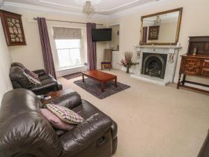 a living room with a leather couch and a fireplace at Gower View in Tenby