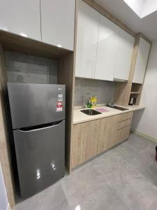 a kitchen with a stainless steel refrigerator and white cabinets at Melaka Imperio Residence with Wifi and PoolSeaview in Malacca