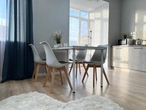 einen Esstisch mit weißen Stühlen und eine Küche in der Unterkunft LUX в новом ЖК in Pawlodar