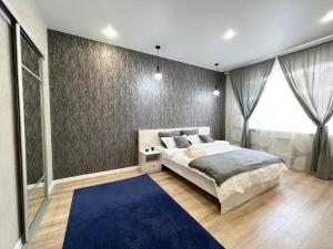 a bedroom with a large bed and a blue rug at LUX в новом ЖК in Pavlodar