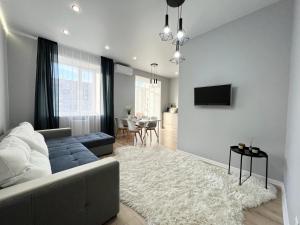 ein Wohnzimmer mit einem Sofa und einem TV an der Wand in der Unterkunft LUX в новом ЖК in Pawlodar