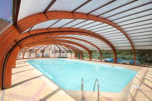 einen großen Pool mit gewölbter Decke in der Unterkunft Les Chalets de la MARGERIDE in Blavignac