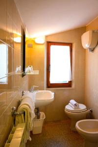 een badkamer met een wastafel, een toilet en een raam bij Affittacamere Dal Falco in Pienza