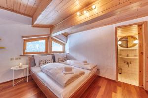 Cama grande en habitación con techo de madera en Marys Holiday Penthouse, en Saalbach Hinterglemm