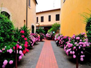 a pathway lined with pink flowers in a courtyard at Affittacamere Dal Falco in Pienza