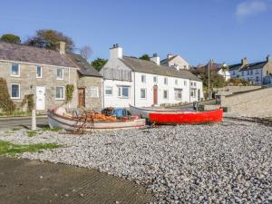 two boats sitting on a rocky beach next to houses at Bryntirion in Moelfre
