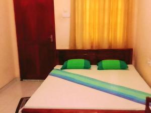 a bedroom with a bed with green pillows at New Green Garden Hotel & Safari in Tissamaharama
