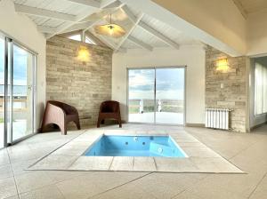 a living room with a blue tub in a room with windows at Cabaña con spa Vida Abundante in Villa Yacanto