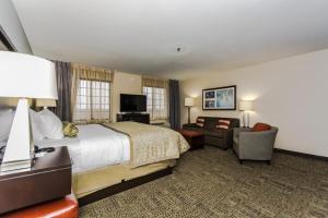 Staybridge Suites Grand Forks, an IHG Hotel في غراند فوركس: غرفة في الفندق بسرير وكرسي وأريكة