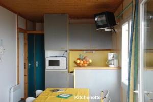 eine kleine Küche mit einem Tisch und einer Mikrowelle in der Unterkunft Les Chalets de la MARGERIDE in Blavignac