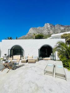 eine Terrasse mit Stühlen und Tischen sowie ein Gebäude in der Unterkunft Four Uitsig Camps Bay in Kapstadt