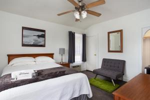 Travel Inn of Titusville في تيتوسفيل: غرفة نوم بسرير وكرسي ومروحة سقف