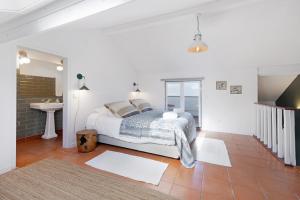 a white bedroom with a bed and a sink at Casa da Praia in Alcochete