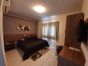 Dormitorio con cama negra y TV en Matinada Palace Hotel, en Paraguaçu