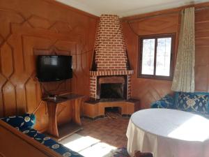 a living room with a fireplace and a tv at Gite Oukaimeden in Oukaïmeden
